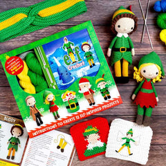 Crochet elf kit with yarn, pattern book, and completed crochet elves on a wooden surface.