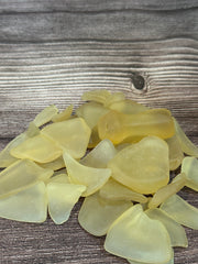 Close up of a pile of citrus colored seaglass set on a wooden background.