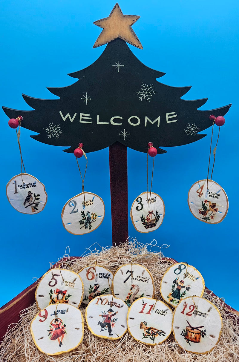 Hand-painted sand dollar ornaments featuring classic 12 Days of Christmas designs