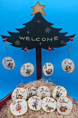Hand-painted sand dollar ornaments featuring classic 12 Days of Christmas designs