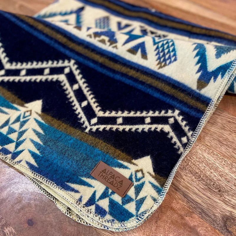 Extreme close-up of the corner of the Blue/Cream Alpaca Baby Blanket, showing the weave and signature tag.