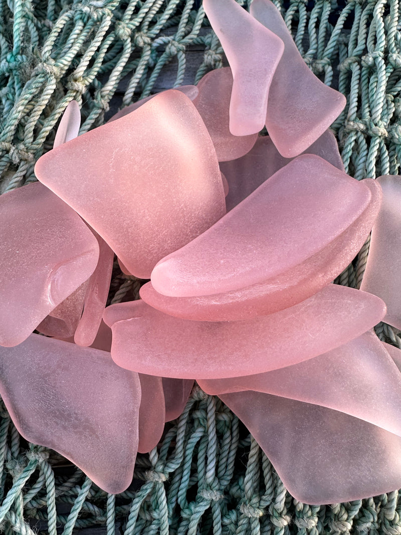 a close up of blush sea glass on a net