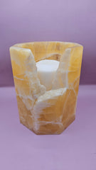 Honeycomb calcite candle cover with translucent golden tones and a hexagonal shape, measuring 6.75x5.5 inches.