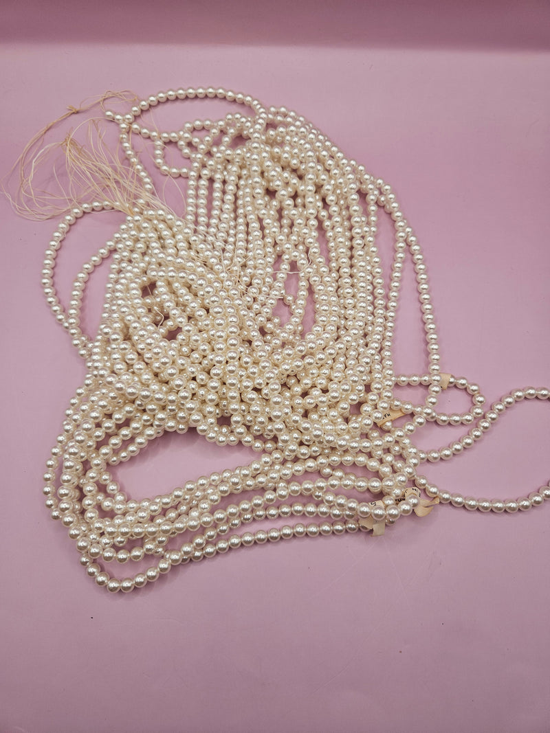 Vintage string of pearls, approximately 58 inches, laid out for crafting or jewelry making.