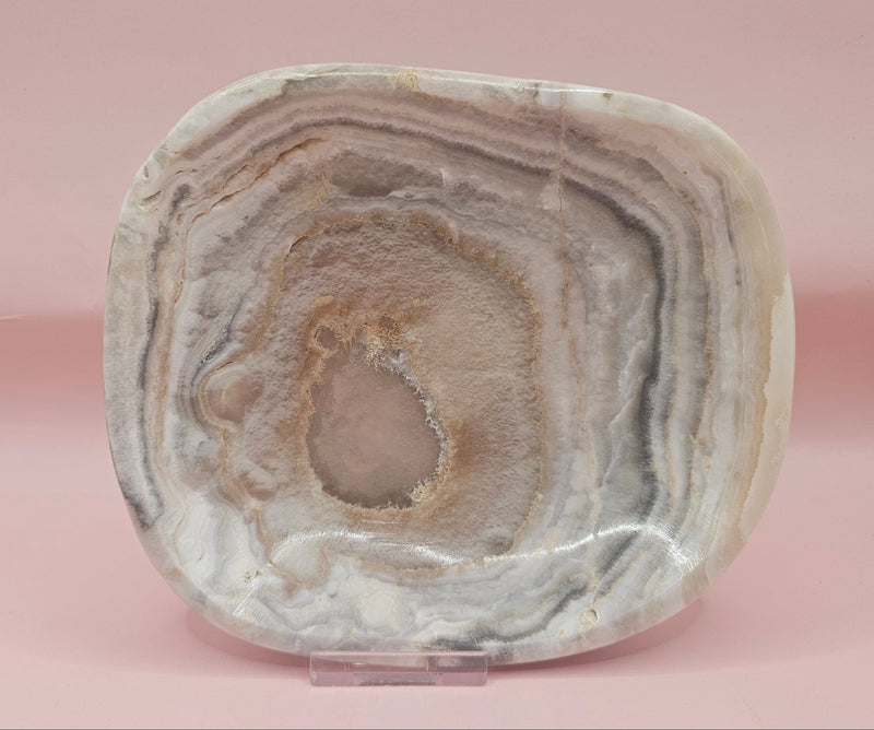 Polished 6x5" onyx dish with natural concentric banding and textured center on pink background