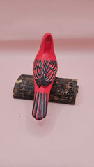 Photo of hand-carved wooden cardinal figurine, painted in bright red with black detailing, perched on a unique natural wood base.