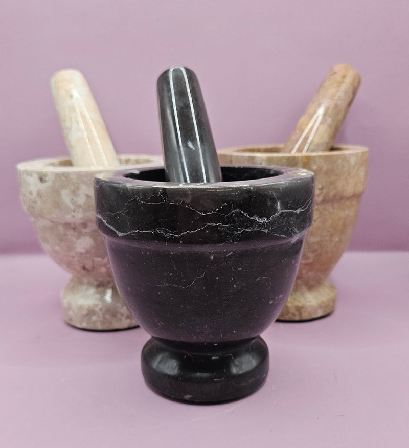 Three stone mortar and pestle sets in beige, brown, and black, featuring a durable design for grinding spices and herbs.