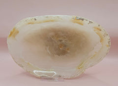 Creamy raw-edge onyx dish with soft golden veining and irregular shape on pink background