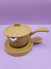 Vintage mustard yellow Descoware butter warmer with lid and trivet, cast iron design.