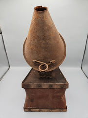 A vintage metal beekeeping smoker with a cone-shaped spout and rectangular body. The piece has a rustic, aged patina with visible rivets, making it a unique collectible or décor item for vintage and industrial-themed spaces