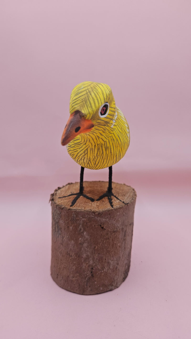 Hand-painted yellow bird figurine on wood stump with pink background – folk art decor