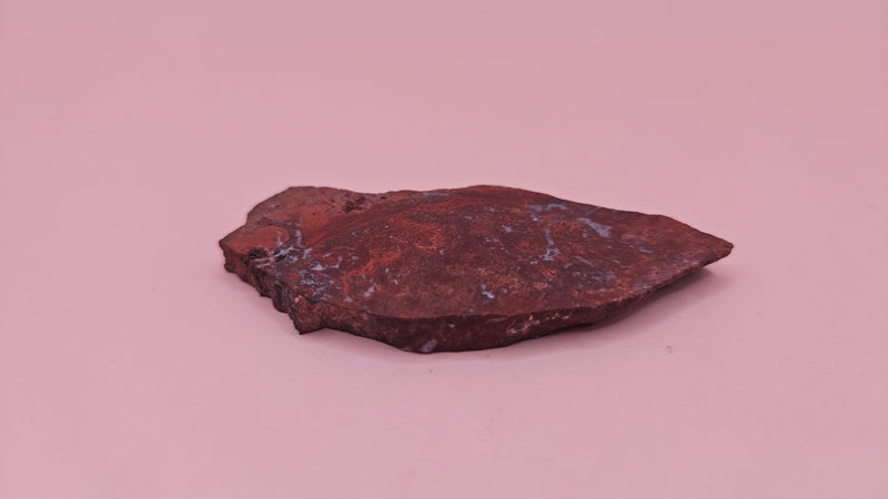 Moss Agate slab 22g, reddish with blue-white moss-like inclusions, 2.6x1.3 inches, photographed on pink background.