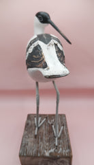 Hand-carved wooden avocet bird sculptures with black and white detailing on rustic stands