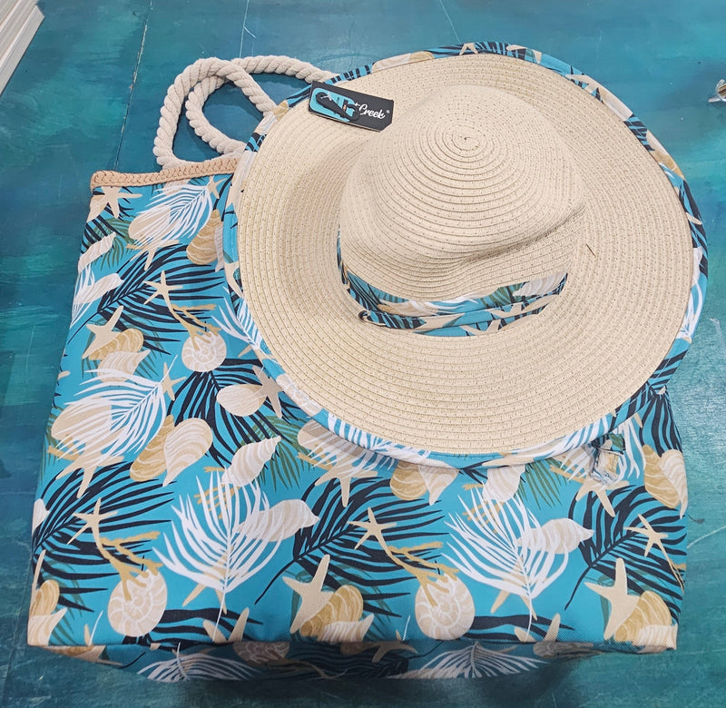 Close-up of teal beach bag with rope handles and seashell, starfish, and palm print, stacked over navy palm print bag.