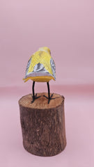 Hand-painted yellow bird figurine on wood stump with pink background – folk art decor
