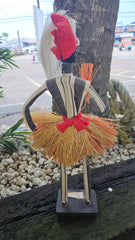 Handcrafted African tribal doll sculpture with straw skirt, cowrie shells, and a tall headdress, mounted on a wooden base.