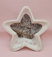 Dark polished onyx star dish with gray and brown veining on pink background