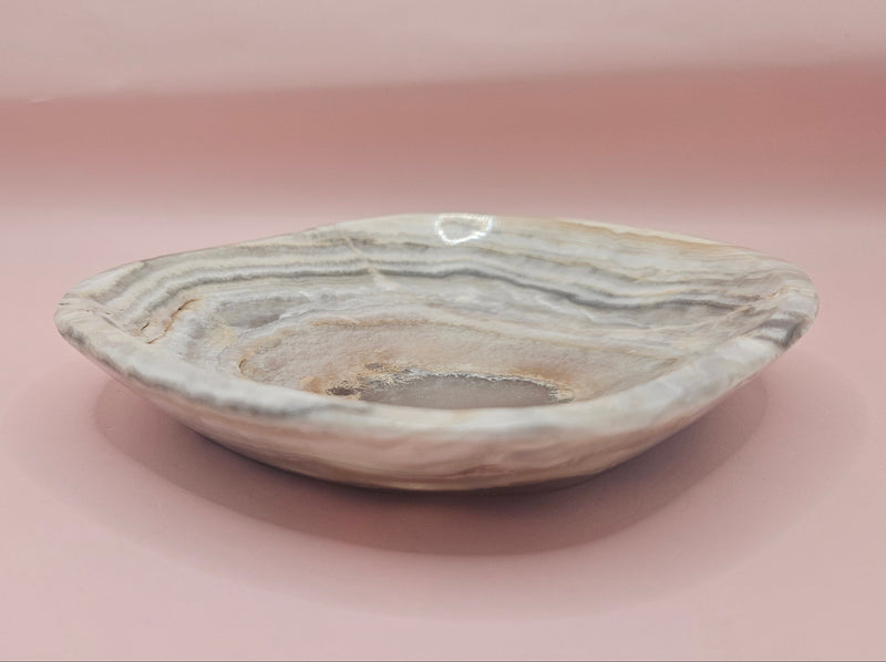 Polished 6x5" onyx dish with natural concentric banding and textured center on pink background