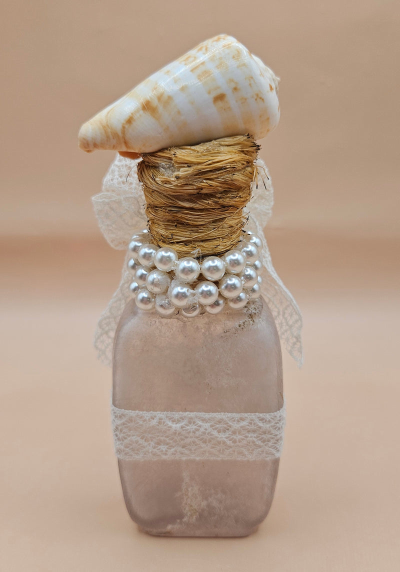 Vintage 5.5"x2" decorative bottle with a spiral seashell top, lace bow, pearl accents, and gold starfish charm against a neutral background