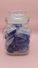 Vintage glass jar with cobalt and frosted sea glass, floral lid detail, ocean-inspired coastal decor on pink background