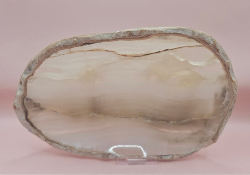 polished onyx oval dishes with gray and cream veining displayed on a pink background
