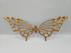 A brass butterfly sculpture with sleek mid-century modern design. The butterfly features smooth, elongated wings and a minimalist aesthetic, measuring 10.25 inches long by 4 inches wide. The metallic finish adds a vintage touch, perfect for home décor or display on a shelf or table