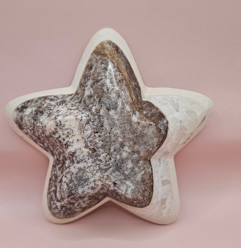 Dark polished onyx star dish with gray and brown veining on pink background