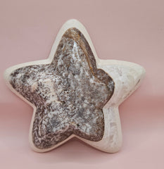 Dark polished onyx star dish with gray and brown veining on pink background