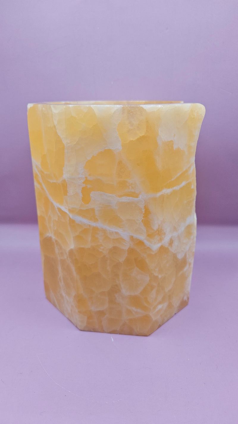 Honeycomb calcite candle cover with translucent golden tones and a hexagonal shape, measuring 6.75x5.5 inches.