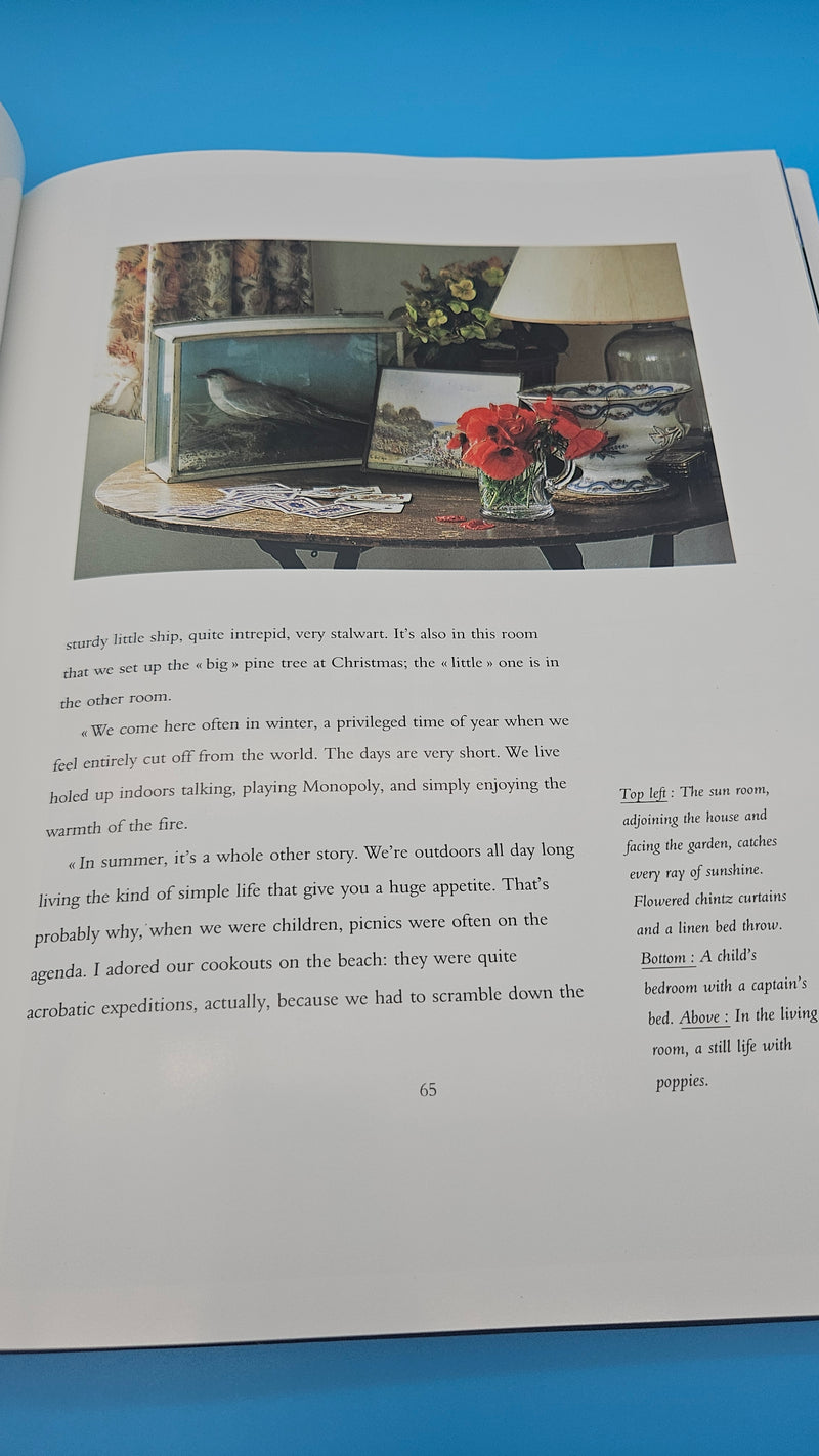 Hardcover of Family Houses by the Sea showing a child reading on a floral daybed inside a green-painted seaside cottage with white trim and sunlit windows.