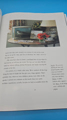 Hardcover of Family Houses by the Sea showing a child reading on a floral daybed inside a green-painted seaside cottage with white trim and sunlit windows.