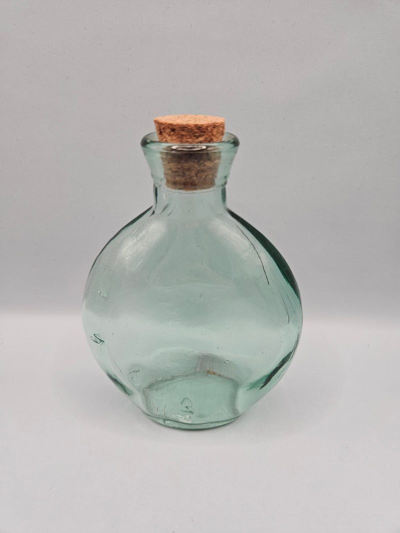 Vintage clear glass bottle with round design and cork stopper, 4.5 inches tall by 3.5 inches wide.