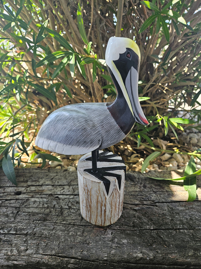 Carved wooden pelican decor in three sizes, small (11.5 x 7 inches), medium (14 x 9.5 inches), and large (17.75 x 11 inches), perfect for coastal decor