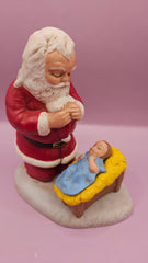 Hand-painted Spirit of Christmas figurine featuring Santa kneeling before baby Jesus in a manger, measuring 5.75x5 inches, heartfelt holiday decoration.