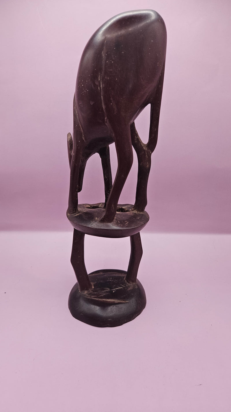 Vintage hand-carved wooden antelope sculpture, measuring 11"x3.5", featuring intricate details on a pink background.