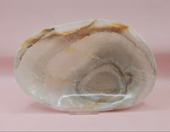 polished onyx oval dishes with gray and cream veining displayed on a pink background
