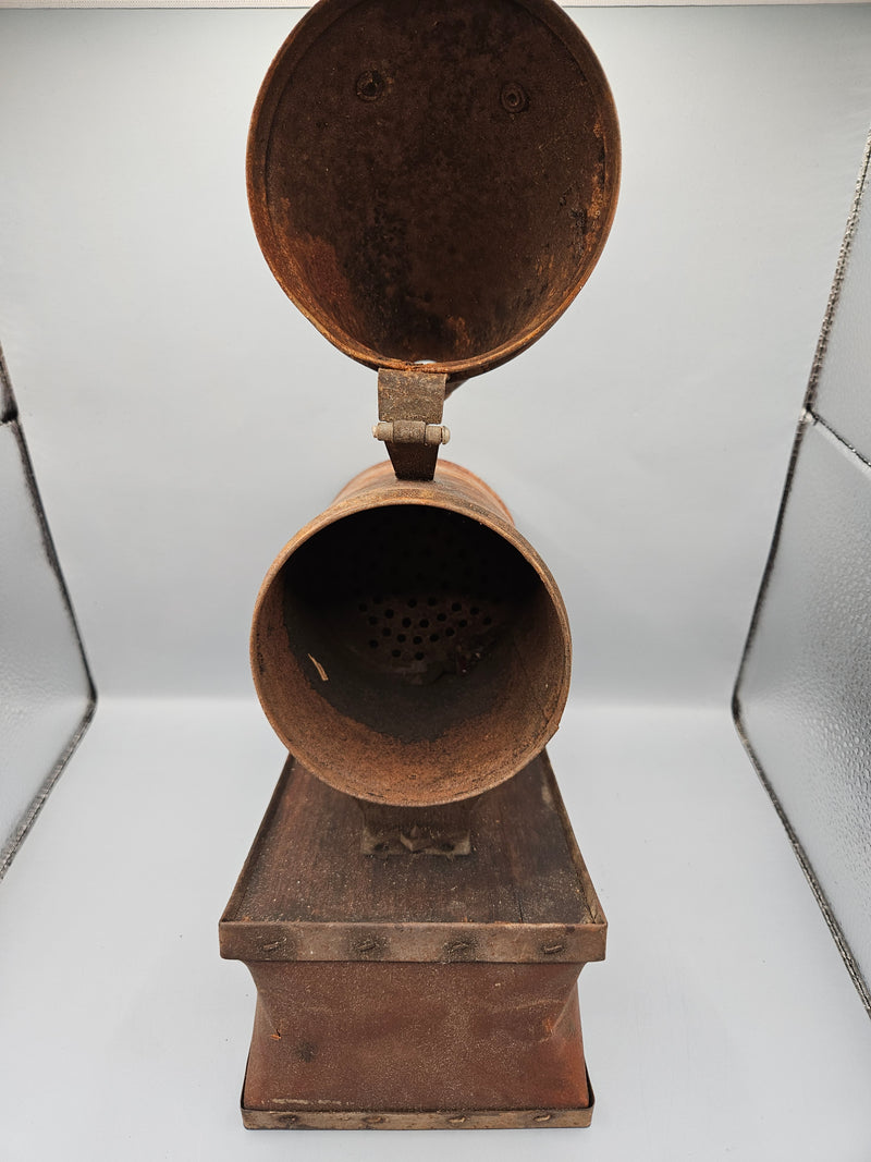 A vintage metal beekeeping smoker with a cone-shaped spout and rectangular body. The piece has a rustic, aged patina with visible rivets, making it a unique collectible or décor item for vintage and industrial-themed spaces