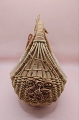 Vintage handwoven wicker basket in the shape of a rabbit with detailed ears and handle, photographed against a pink background.
