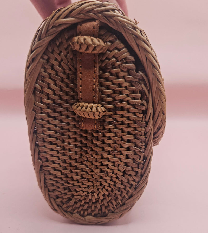 Handwoven rattan clutch with leather strap closure