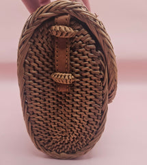 Handwoven rattan clutch with leather strap closure