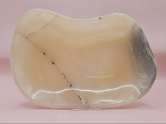 Polished onyx dish with cream and charcoal veining on pink background