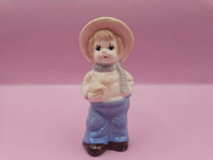 Vintage 1970s Boy with Sparrow ceramic figurine, featuring a boy in a wide-brimmed hat and scarf, displayed with original black packaging