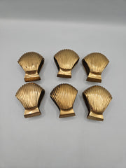 Close-up of a set of 6 vintage brass clam shell napkin rings, showing their intricate design and aged brass finish. Perfect for adding elegance and a touch of coastal charm to table settings