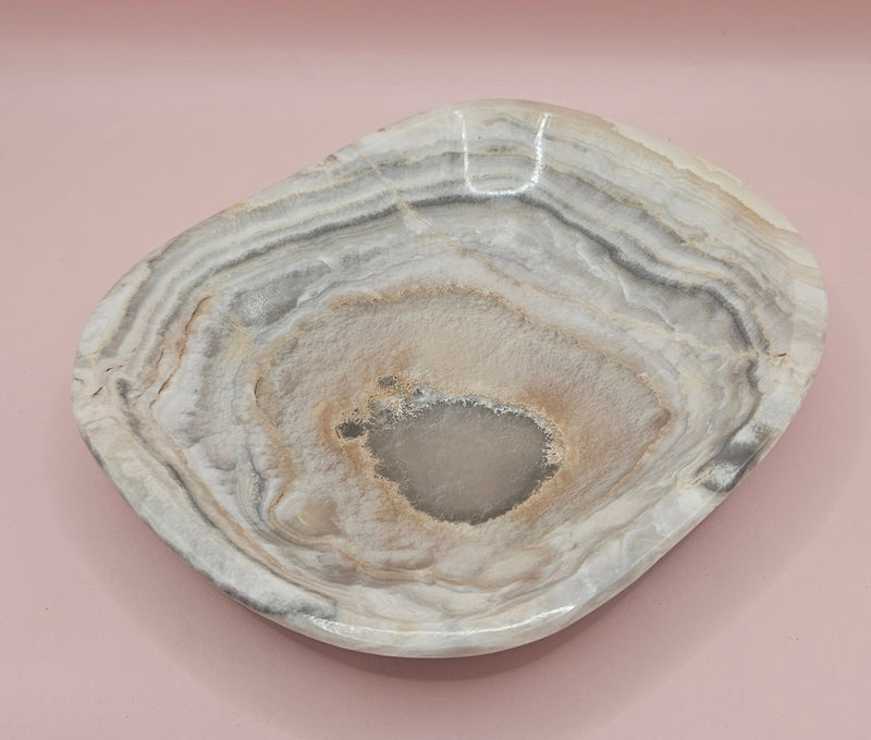 Polished 6x5" onyx dish with natural concentric banding and textured center on pink background