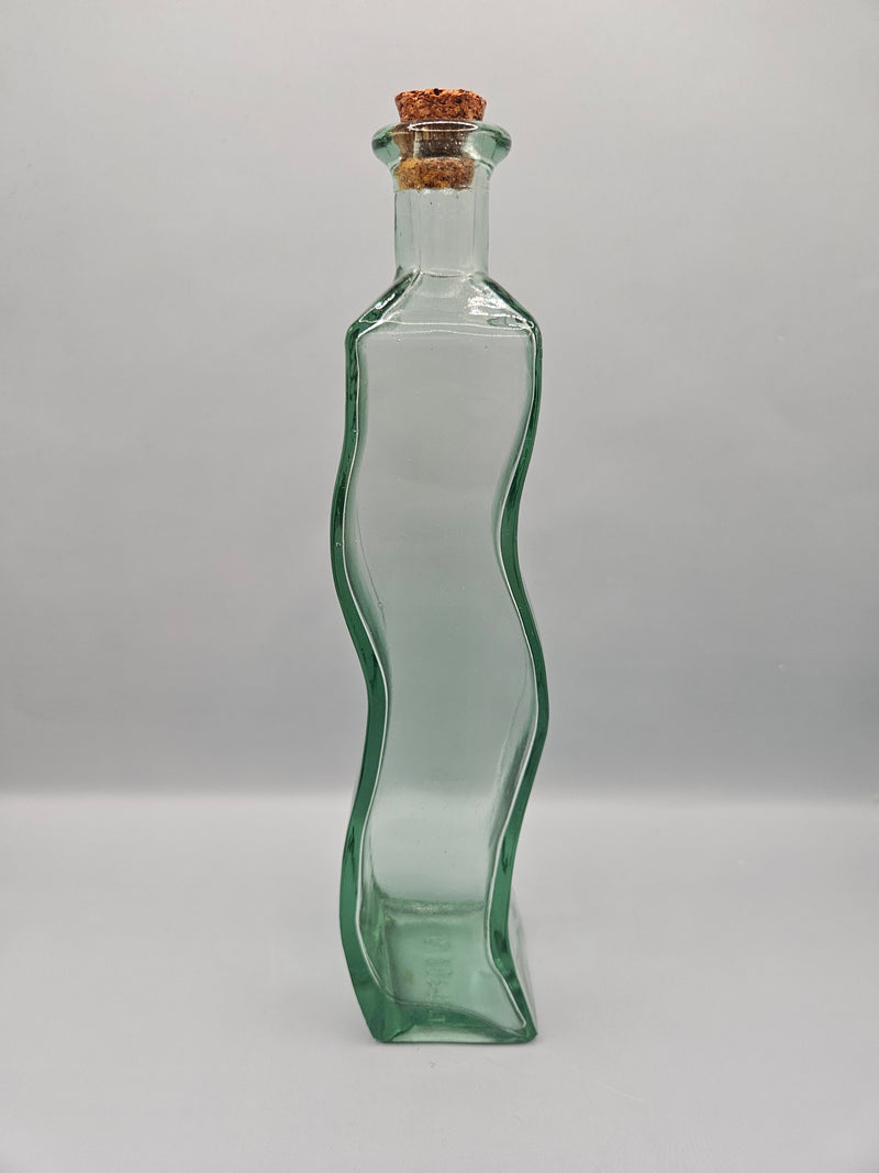 Vintage wavy glass bottle with a cork stopper, 9.25 inches tall by 2 inches wide, perfect for home décor or use as a small vase.