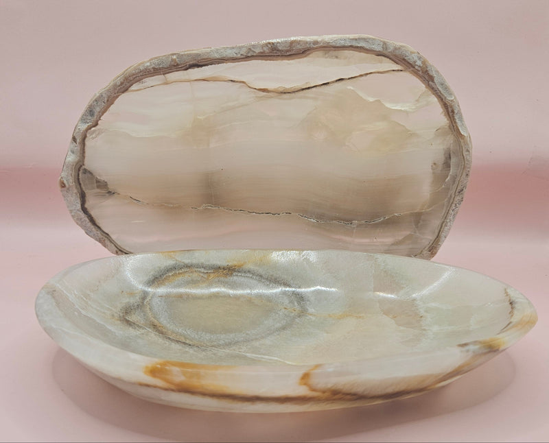 polished onyx oval dishes with gray and cream veining displayed on a pink background