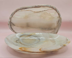 polished onyx oval dishes with gray and cream veining displayed on a pink background