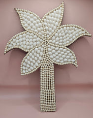 Handmade palm tree wall art made of natural white shells with beaded detailing on a pink background.