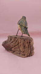 Handmade green songbird figurine with yellow and brown details, perched on a natural wood stump, 5x4 inches.