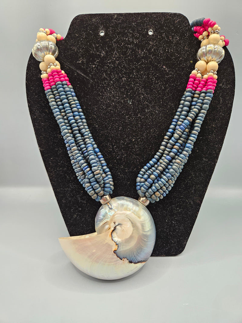 multistrand necklace featuring dark beads with pink, silver, and natural wood accents. The necklace is highlighted by a large, natural Nautilus shell pendant, offering a unique bohemian style. Perfect for casual or beach-inspired looks.